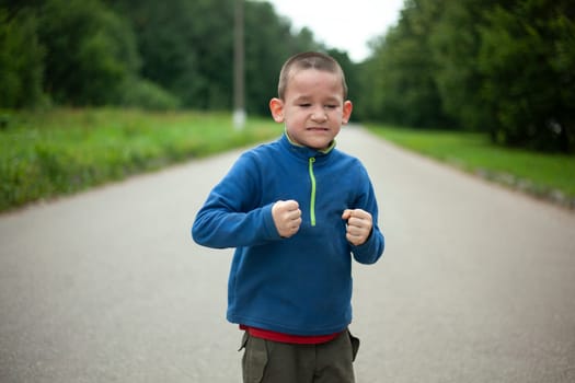 Child is angry. Boy threatens. Schoolboy swears in street. Negative emotions in child.