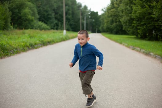 Child runs down road. Boy in summer. Schoolboy on street. Street boy in town.