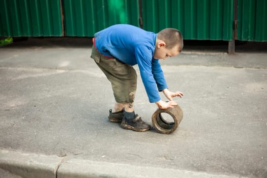 Child is holding dirty object. Little boy plays with concrete ring. Child found thing. Baby's adventure in summer.