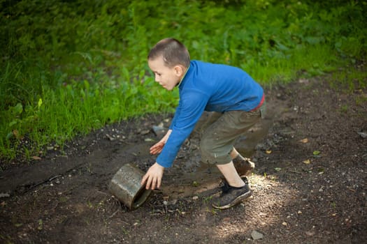 Child is holding dirty object. Little boy plays with concrete ring. Child found thing. Baby's adventure in summer.