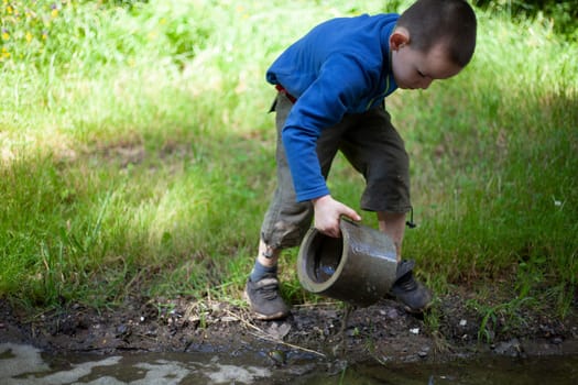 Child is holding dirty object. Little boy plays with concrete ring. Child found thing. Baby's adventure in summer.