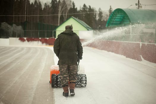Snow removal at ice rink. Removal of layer of snow from ice. Worker cleans stadium of precipitation. Car is snow grinding.