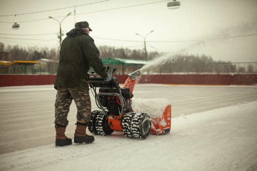 Snow removal at ice rink. Removal of layer of snow from ice. Worker cleans stadium of precipitation. Car is snow grinding.