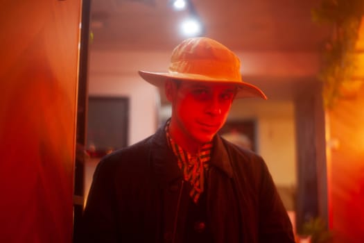 Guy in hat in red light. Man in red interior. Young man indoors. Guy in hat.