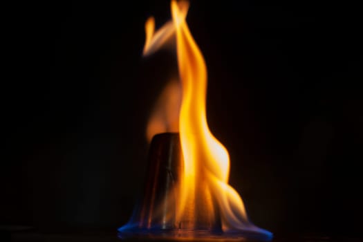 Flames in dark. Tongue of fire one. Alcohol flame retardation. Yellow glow on black background.