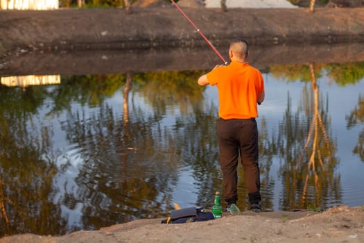 Men are fishing. The guys are fishing with a line. Fishing at sunset on a small pond.