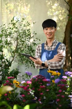 Portrait of Asian man small business entrepreneur in apron using digital tablet at his florist shop.