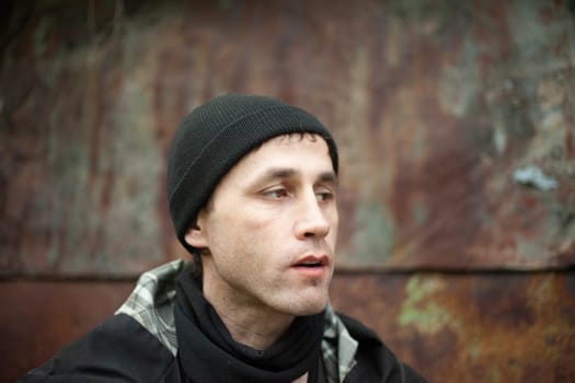 Guy in black hat. Man looks to side. Open mouth in humans. Portrait on street.