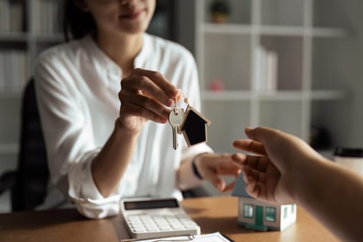 Happy real state agent giving new house key to a young couple. Real estate concept.