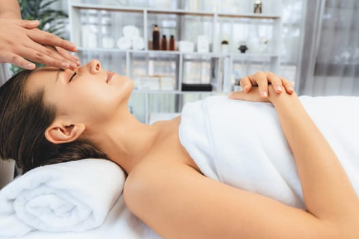 Caucasian woman enjoying relaxing anti-stress head massage and pampering facial beauty skin recreation leisure in dayspa modern light ambient at luxury resort or hotel spa salon. Quiescent