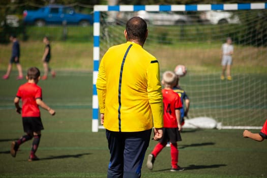 Coach of children's football team. Children's play football. Sports. Details of match.