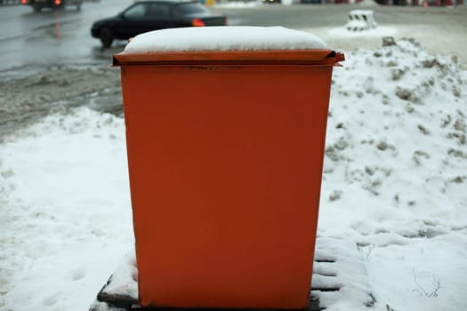 Steel tank. Dumpster. Place to store sand on highway. Orange object in winter on road. Details of road infrastructure.