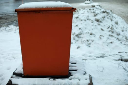 Steel tank. Dumpster. Place to store sand on highway. Orange object in winter on road. Details of road infrastructure.