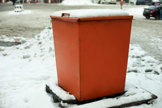 Steel tank. Dumpster. Place to store sand on highway. Orange object in winter on road. Details of road infrastructure.