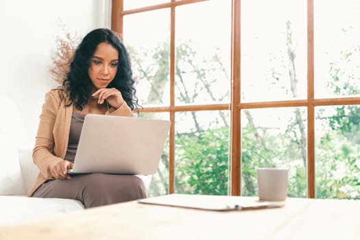 African-American woman using laptop computer for crucial work on internet. Secretary or online content writing working at home.