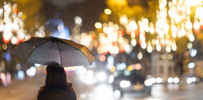 A woman walking down a street holding an umbrella