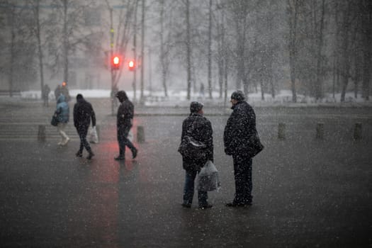 Snow outside. Snowfall in city. People in wet weather. Snowflakes fly in air.