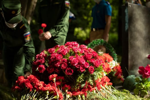 Flowers on grave. Military lay flowers on grave of soldier. Details of ceremony. Military men in dress uniforms.