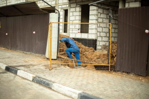 Worker near fence. Builder repairs house. Details of construction of house. Man on set.