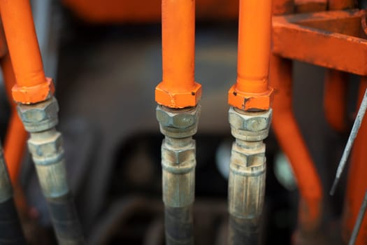 Steel fuel pipes. Tractor parts. Heavy machinery up close. Orange equipment. Hard grip.