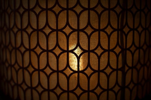 Incandescent lampshade. Texture of lighting fixture. Designer light. Soft light through fabric. Pattern of wood.