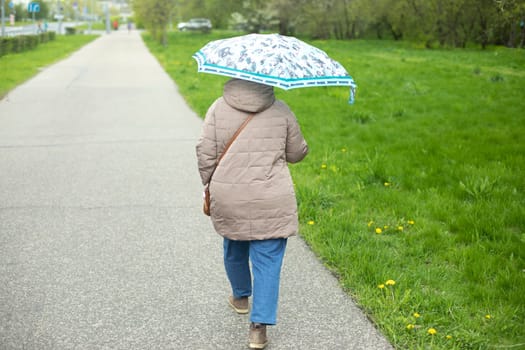 Woman with umbrella in summer. Girl walks through park with umbrella from rain. Walk around city.