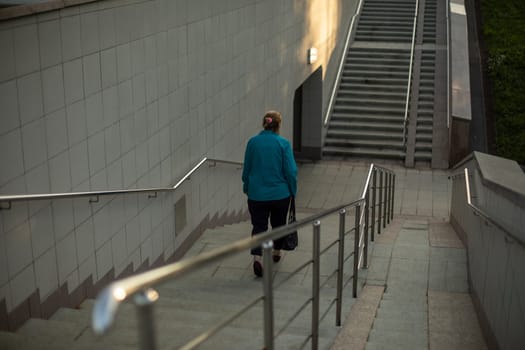 Woman walks up stairs. Pedestrian crossing. Descent to tunnel. Townsman descends steps. Life in city.