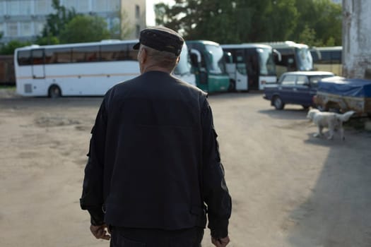 Security guard in parking lot. Man in bus parking lot. Man from behind. Work as security guard in industrial area.