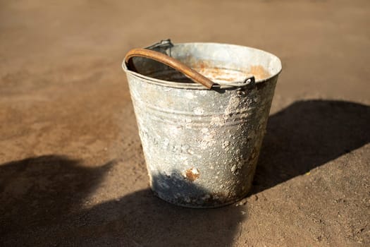 Old bucket outside. Rusty object. Spoiled metal. Junk on street.