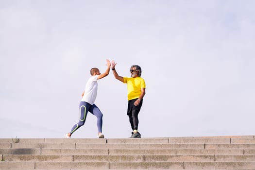 senior man celebrating the success of the effort with a high five with his personal trainer, concept of active and healthy lifestyle in middle age, copy space for text