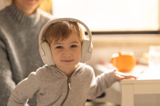 A little boy wearing headphones standing next to a mother