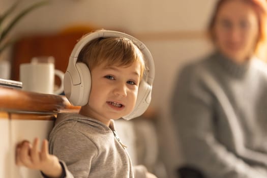 A young boy wearing headphones while standing next to a mother