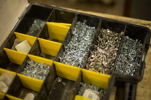 Nuts and bolts in box. Fittings in workshop. Box for tools. Details of items on table.