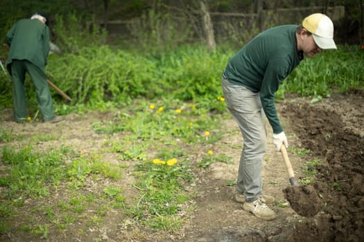 Guy digs soil with shovel. Planting plants in garden. Farming with your own hands.