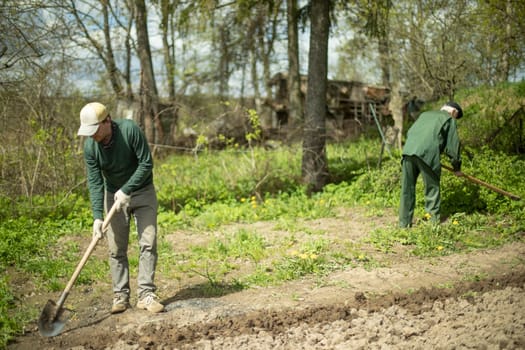 Guy digs soil with shovel. Digging up ground for planting. Work in garden. Life in countryside. Man works.