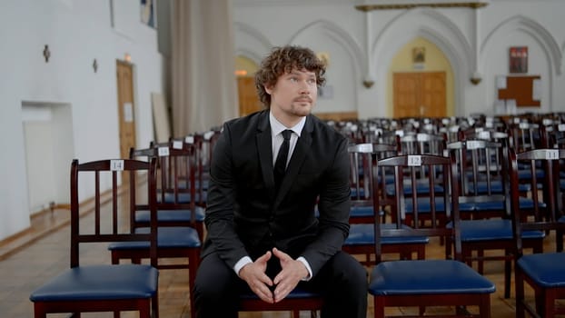 A wedding couple in a church. Action.A young couple is sitting on a decorated chair in wedding costumes and with a wedding white flower. High quality 4k footage