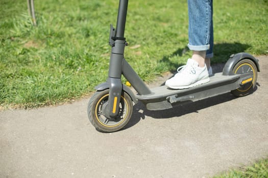 Guy on electric scooter. Man put his foot on platform of scooter. Electric transport in park.