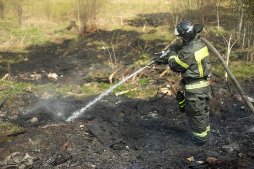 Water pours out of hose. Firefighter holds hydrant. Putting out fire. Rescue service in forest.