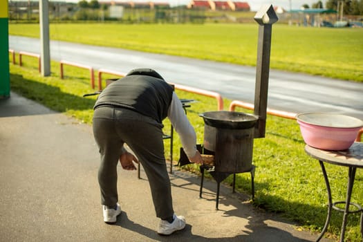 Man uses stove on street. Cooking in park. Smoke exhaust pipe.