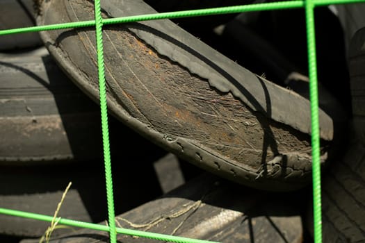 Old tires. Used wheels. Discarded rubber from car. Landfill details. Tire reset mesh.
