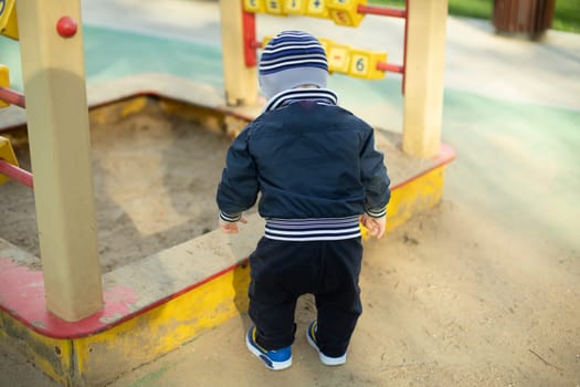 Child in sandbox. Preschooler on playground. Little boy digs ground.