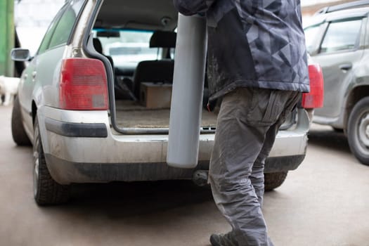 Man puts gas cylinder in trunk of car. Dangerous cargo in transport. Worker transports liquefied gas.