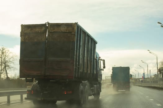 Garbage truck on road. Truck is driving down highway. Garbage can on car. Transportation of waste.