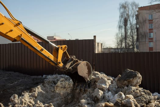 Snow removal on road. Ladle collects snow from chaus. Escalator cleans curbs. Blocks of ice in city.