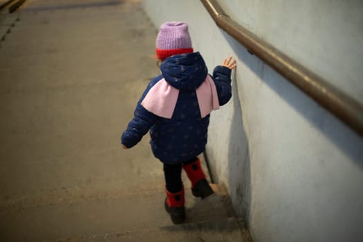 Child goes down stairs. Preschooler walks across pedestrian bridge. Girl walks alone in city.