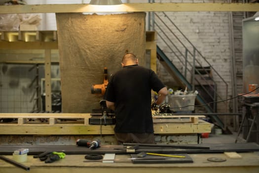 Worker in carpentry workshop. Production room. Guy at desk. Lots of tools in room.