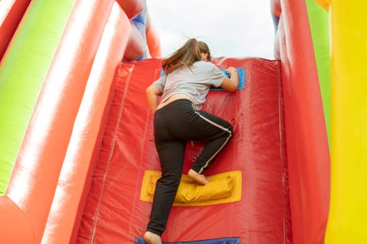 Child climbs slide. Child on obstacle course. Inflatable structure in park of detachments. Children's play.