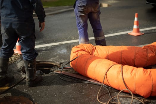 Workers and sewer hatch. Road repairs. Two workers opened hatch on road. Details of work.