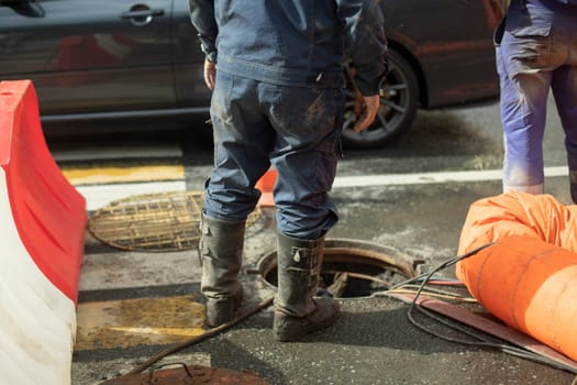 Workers and sewer hatch. Road repairs. Two workers opened hatch on road. Details of work.