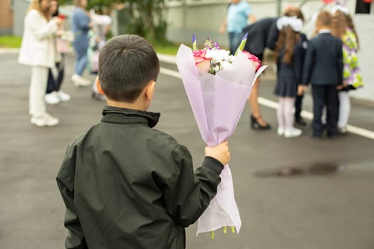 Child holds flowers. Schoolboy with bouquet for teacher. Boy at party. Details of first day of school.